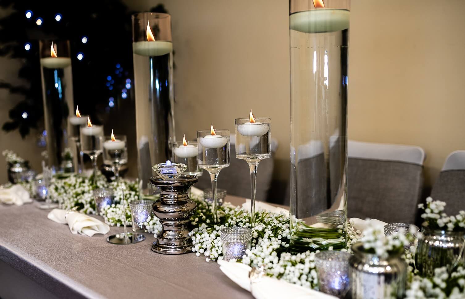 Silver glass pillar candle holders in a long table candlelight setup