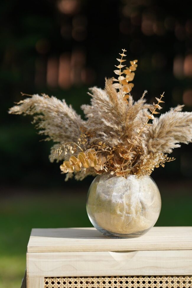 Glass fish bowl vase filled with pampas grass and dried foliage, perfect for boho wedding centrepieces and rustic table décor.