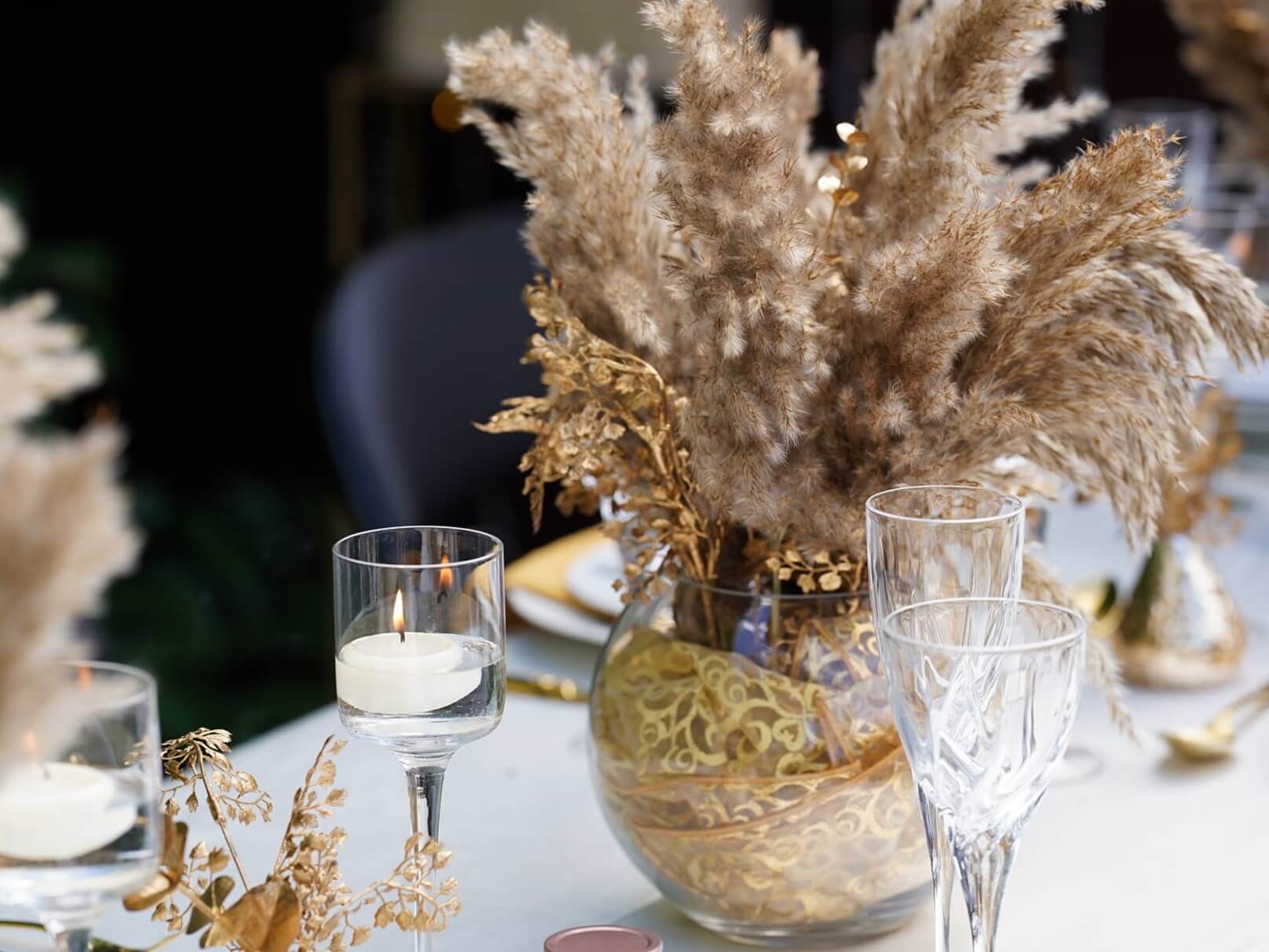Clear glass fish bowl vase styled with dried flowers and gold decorative elements