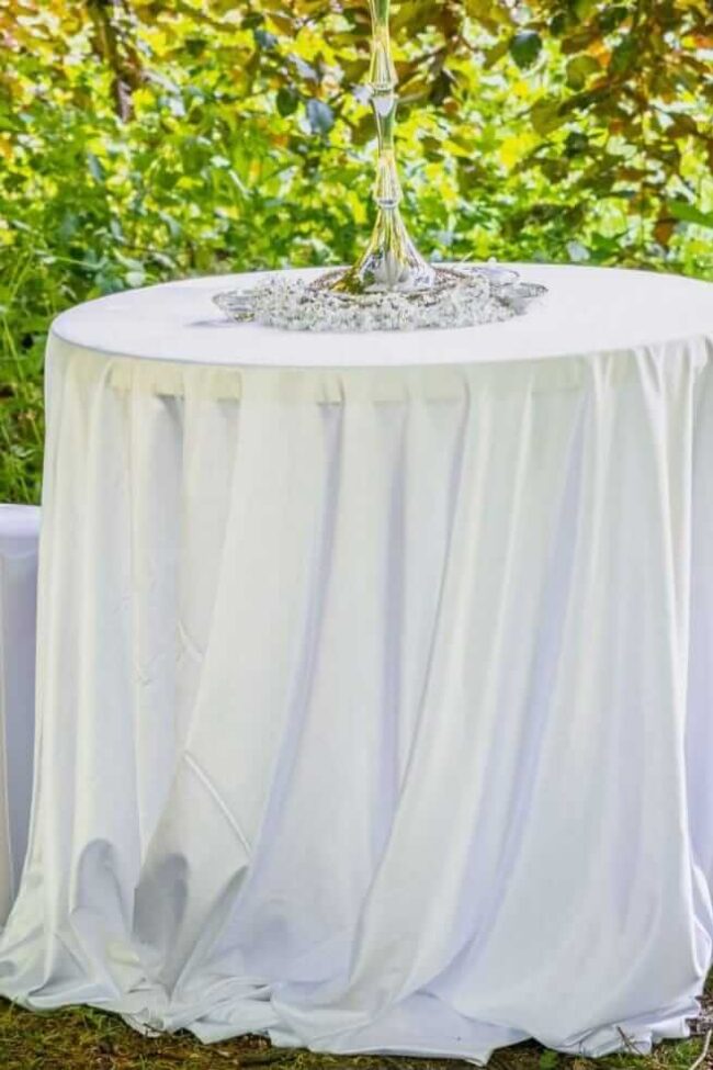 Round white tablecloth covering an outdoor event table
