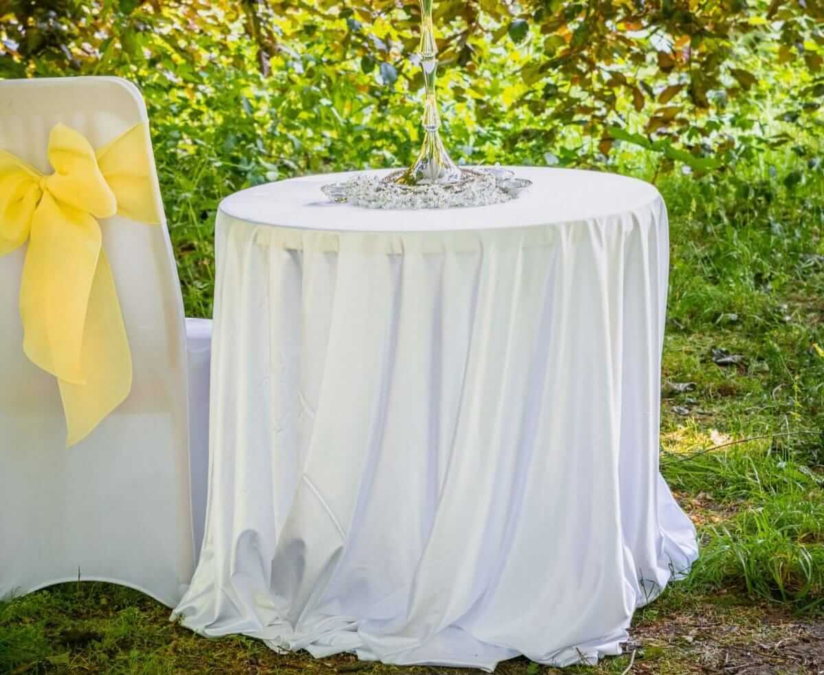 Round white tablecloth covering an outdoor event table