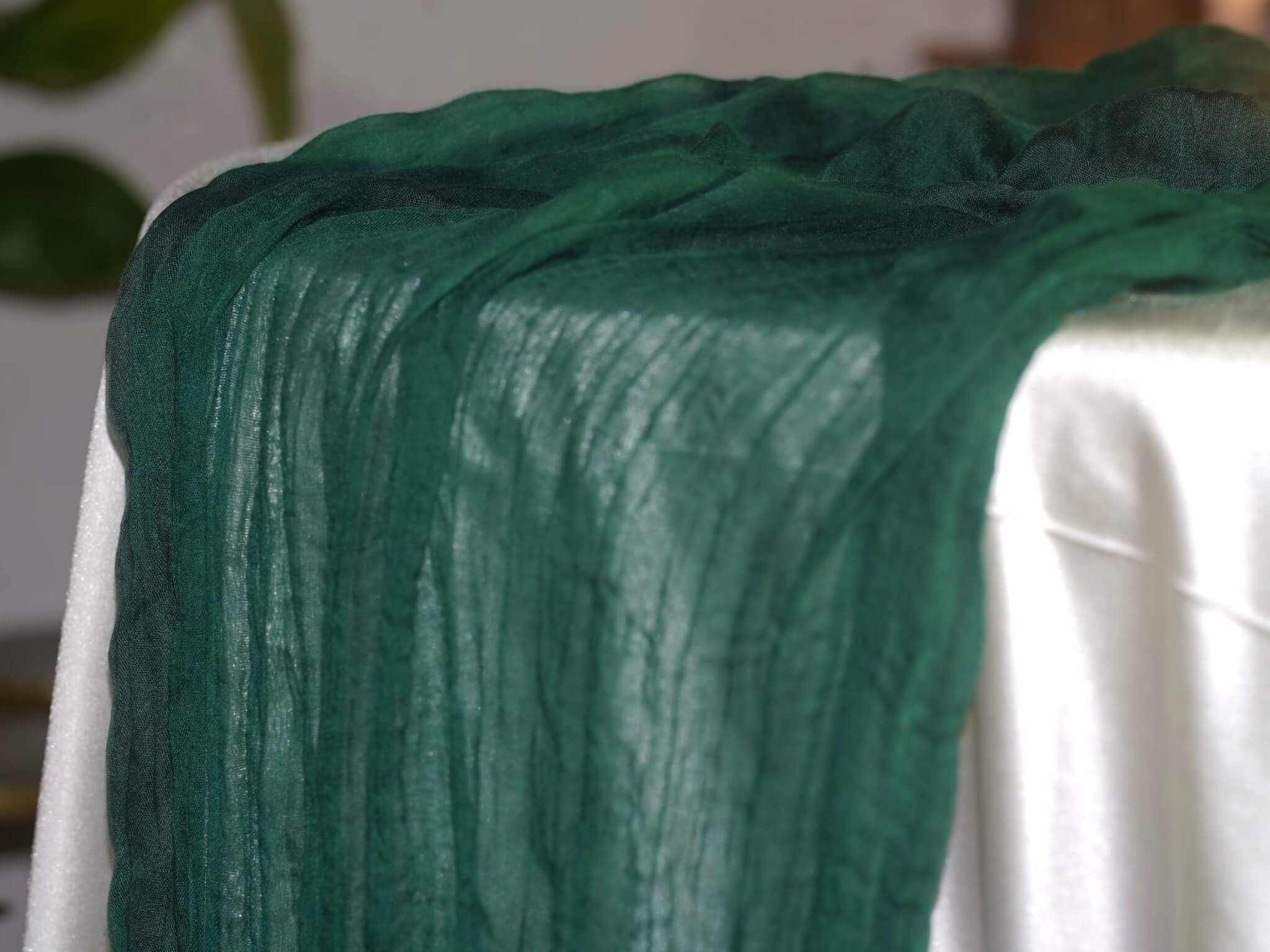 Green cheesecloth runner draped over the edge of a dressed table