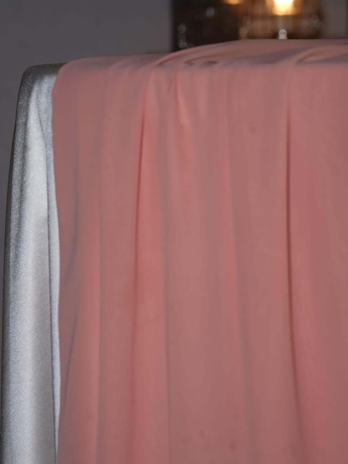 Pink table runner in chiffon fabric draped over the edge of a dressed table