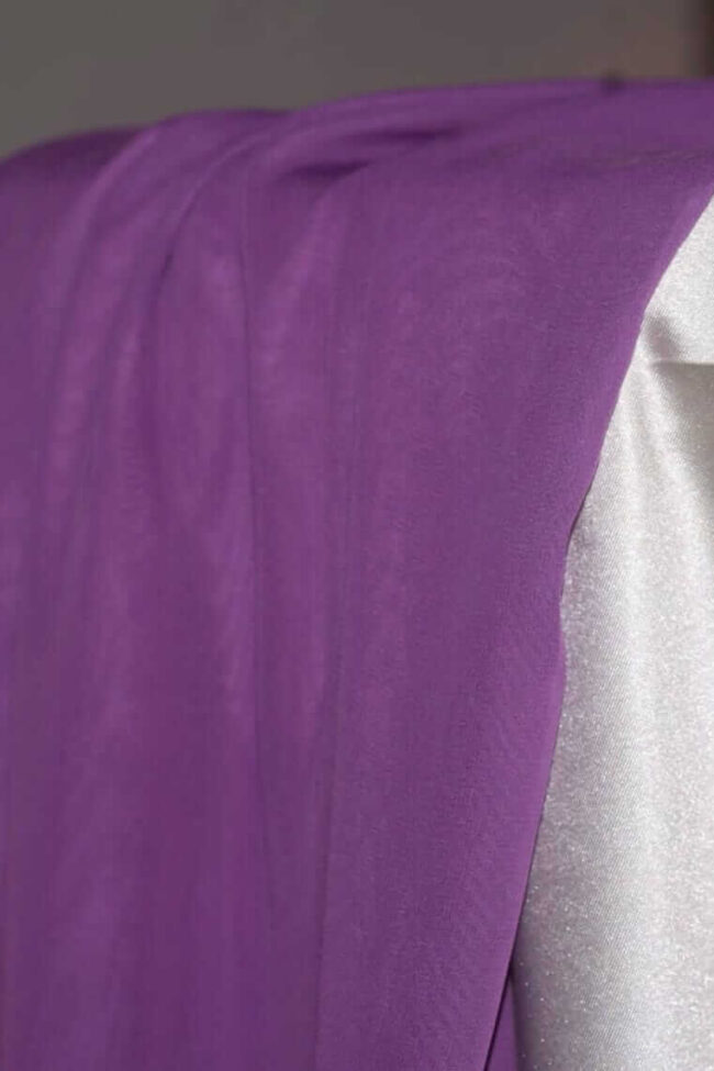 Purple table runners in chiffon fabric draped over the edge of a dressed table