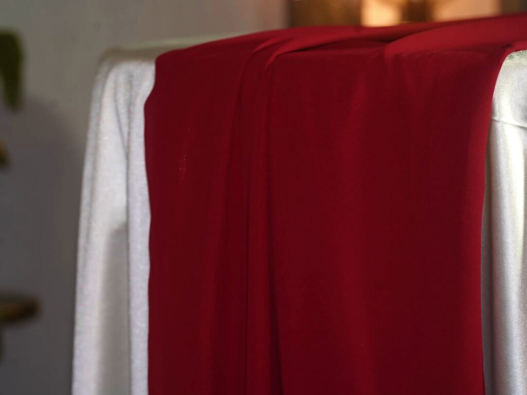 Red table runners in 5m chiffon draped over a dressed table edge