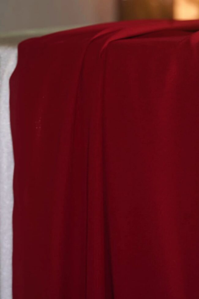 Red table runners in 5m chiffon draped over a dressed table edge