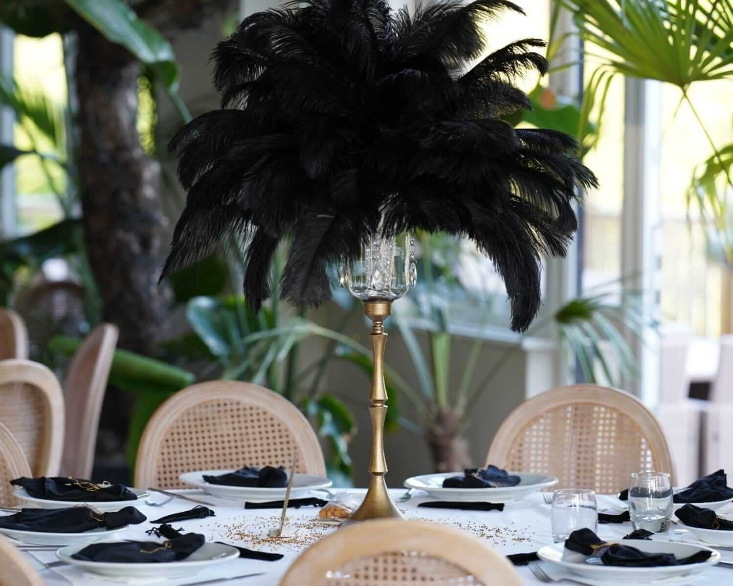 Black napkins styled on wedding place settings with a tall centrepiece