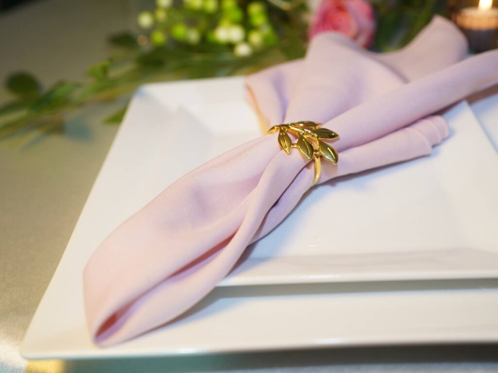 Pink napkins styled with a gold leaf napkin ring