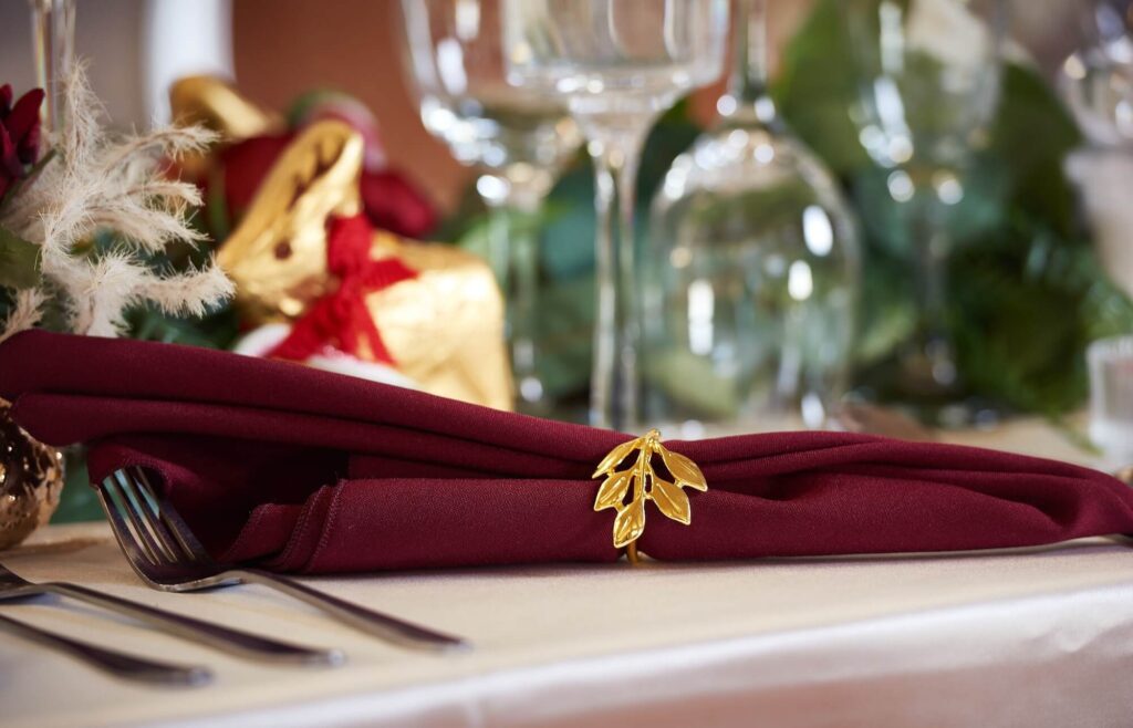 Red napkins in burgundy tone styled with a leaf napkin ring