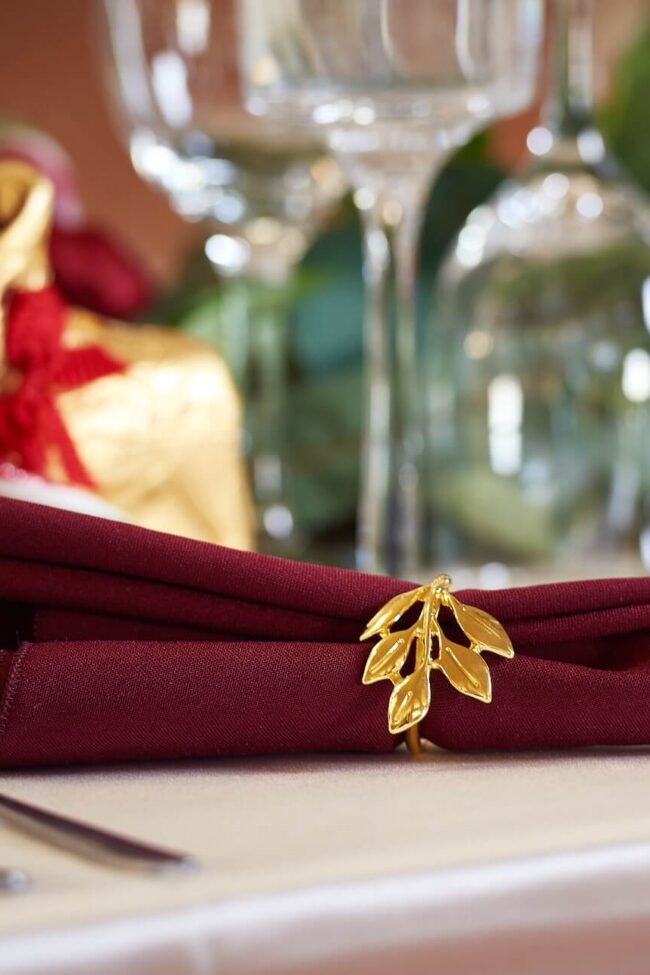Red napkins in burgundy tone styled with a leaf napkin ring