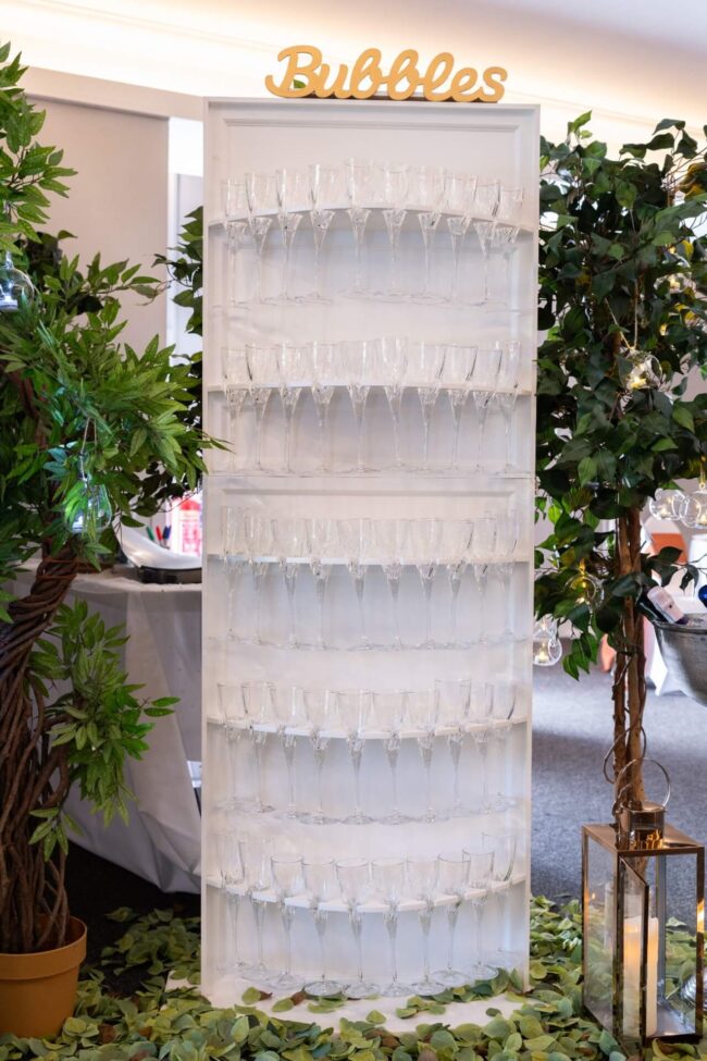 Prosecco wall hire, white drinks wall with flute display