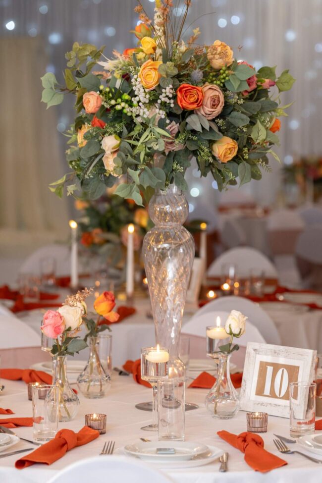Tall artificial flower centrepiece displayed on a tall glass vase for table styling