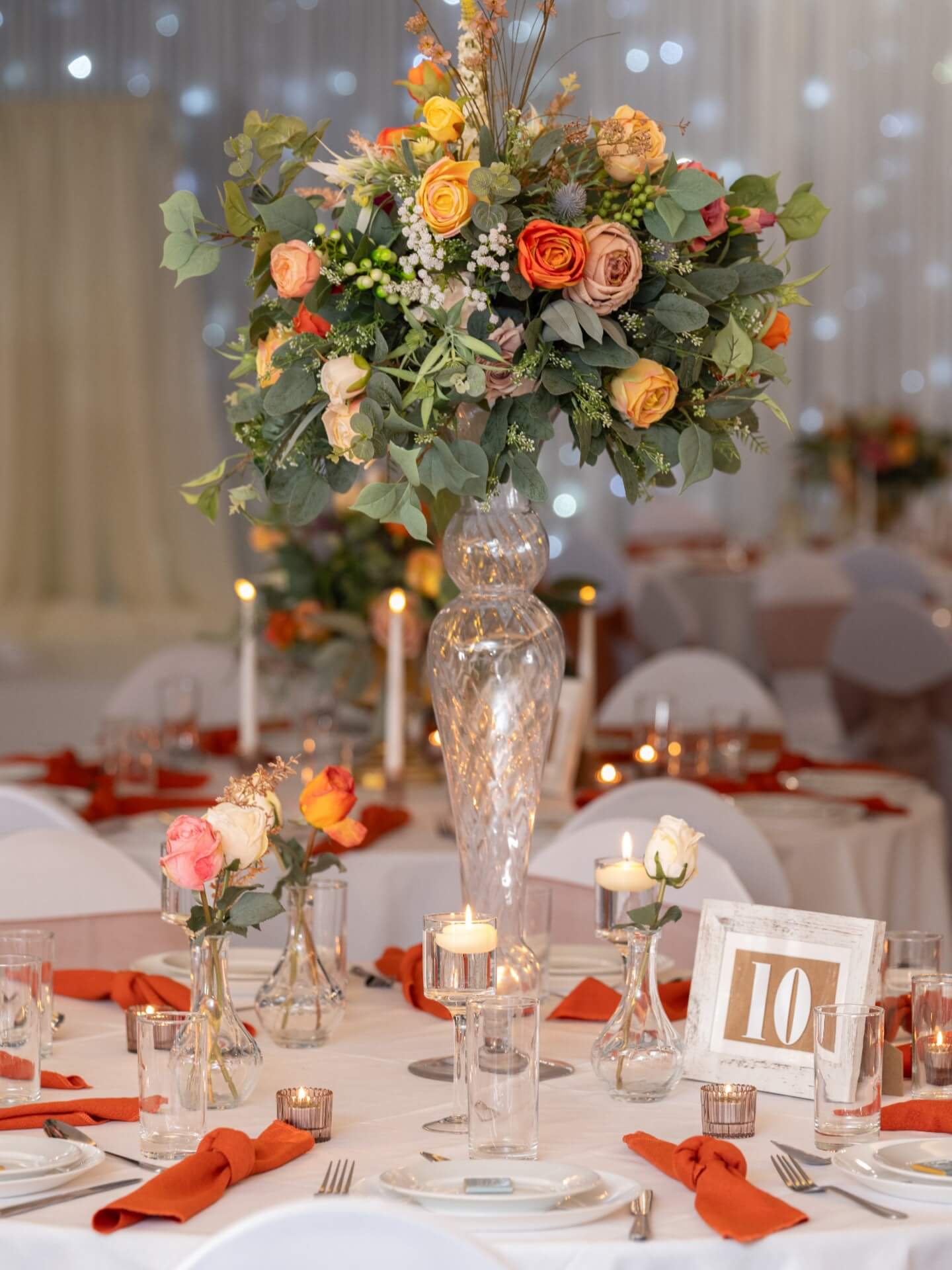 Tall artificial flower centrepiece displayed on a tall glass vase for table styling