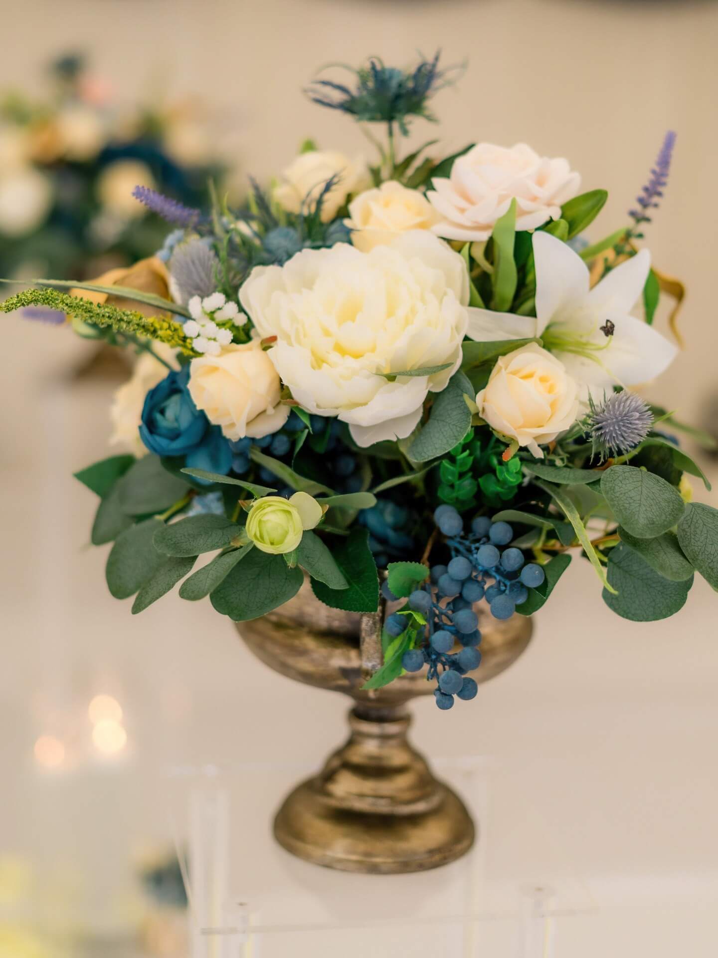 Short artificial flower arrangement displayed in a vintage urn bowl for table styling