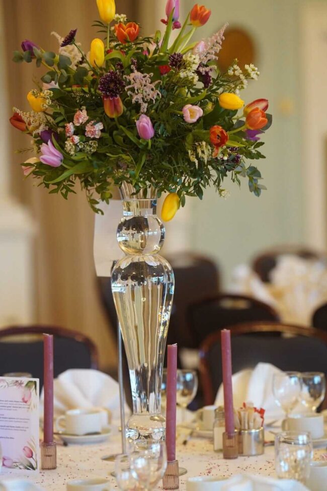 Fresh flower table centerpieces with seasonal blooms on a tall glass vase