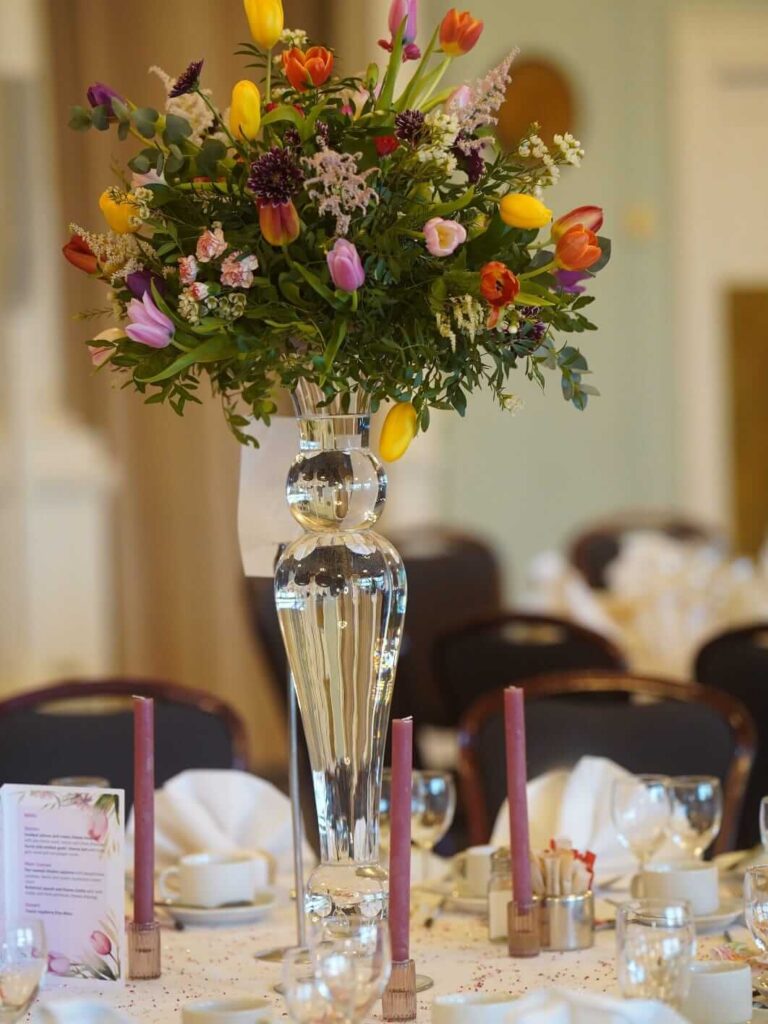 Fresh flower table centerpieces with seasonal blooms on a tall glass vase