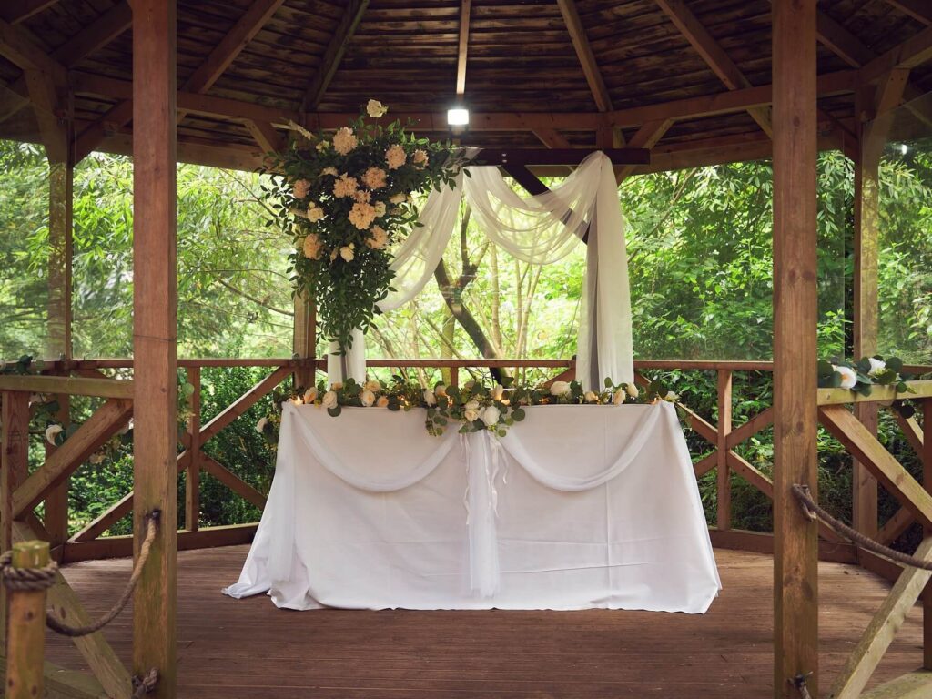Wooden arch hire with white draping and cream flower arrangement