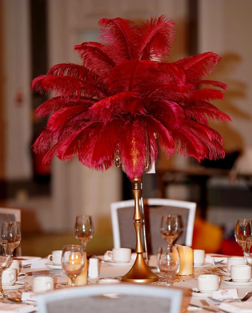 Red feather centrepiece hire styled on a formal dining table