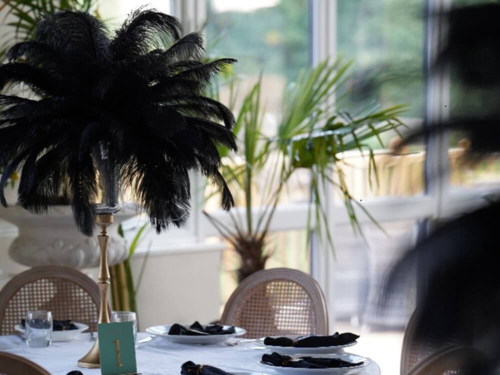 Black feather centrepiece above a white table with black place-setting details