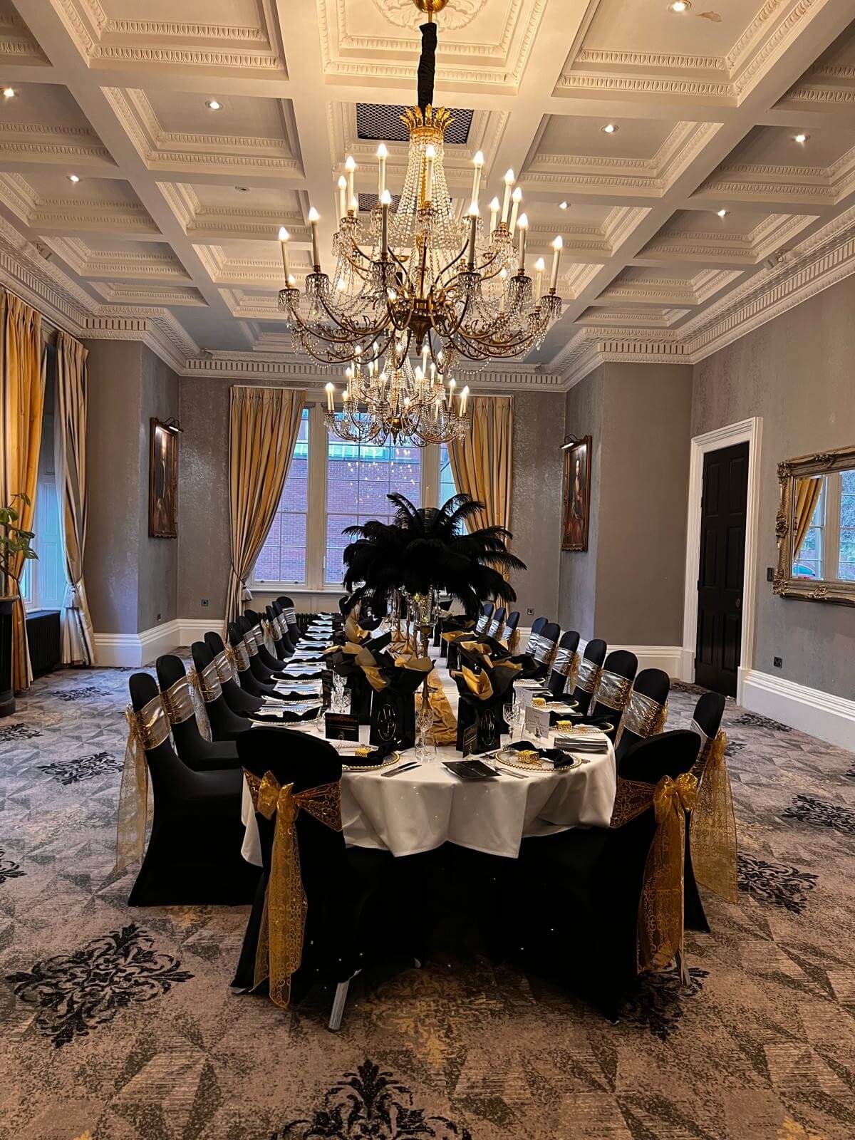 Black feather centrepieces arranged along a formal black-and-gold banquet table