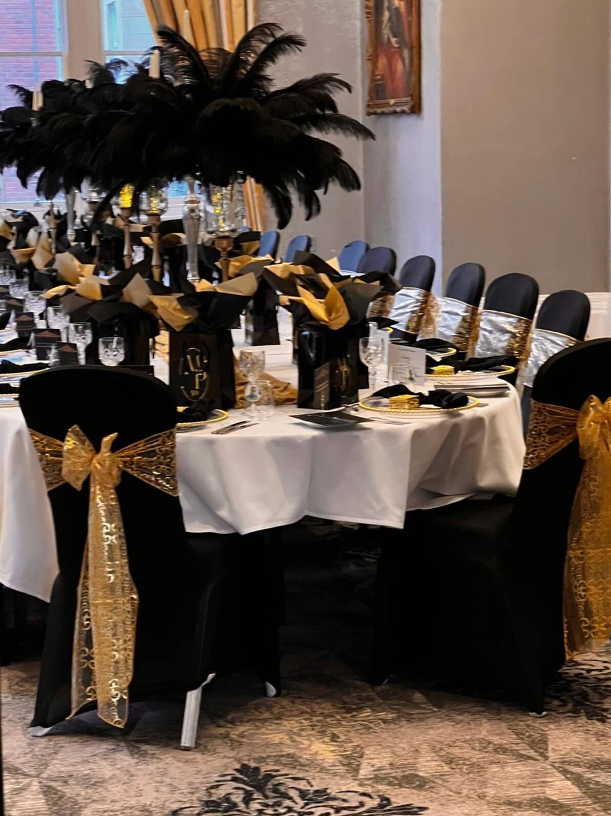 Tall black feather displays above a black, white and gold formal reception table
