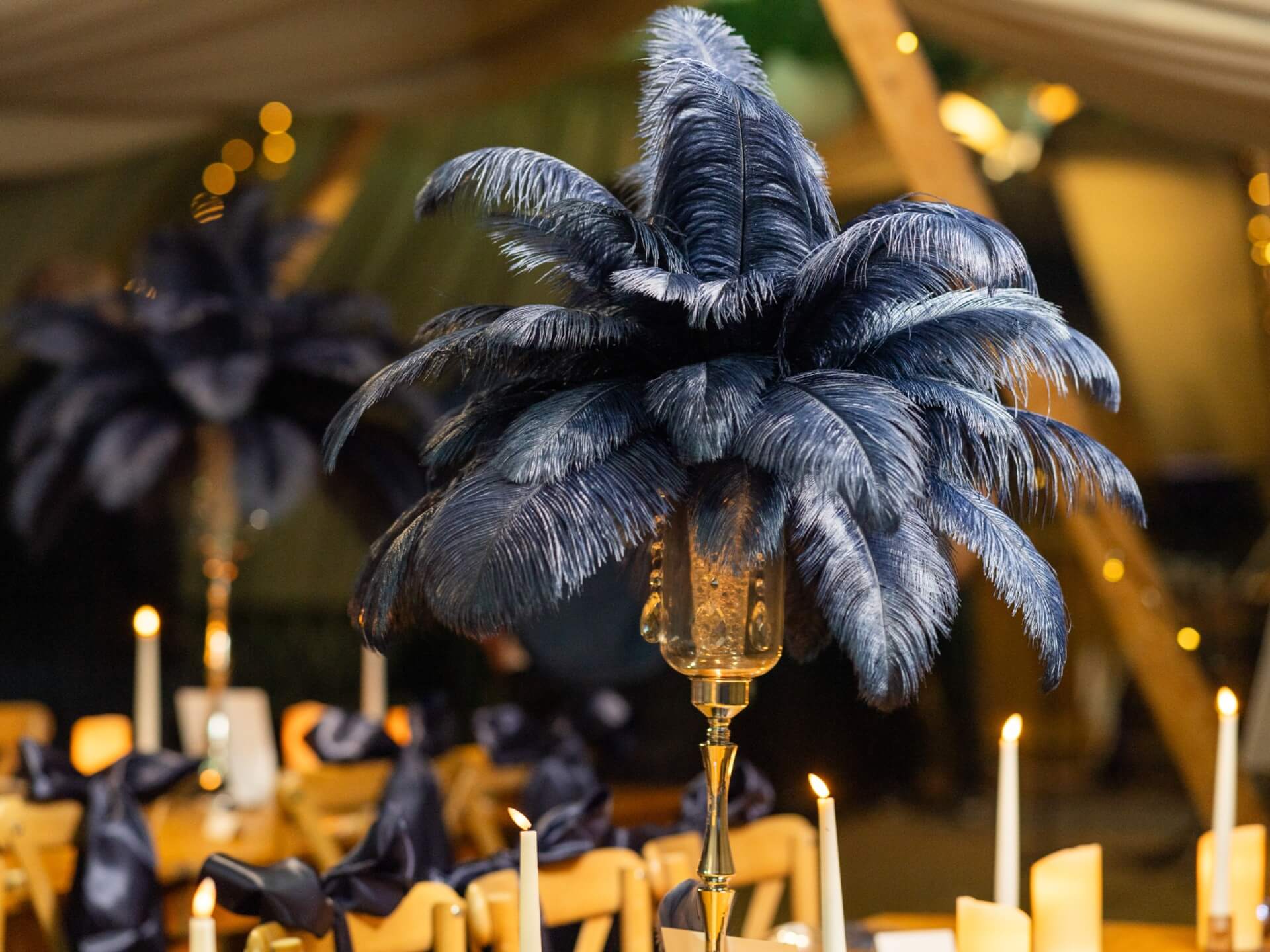Navy blue feather centrepiece displayed above a candlelit evening table