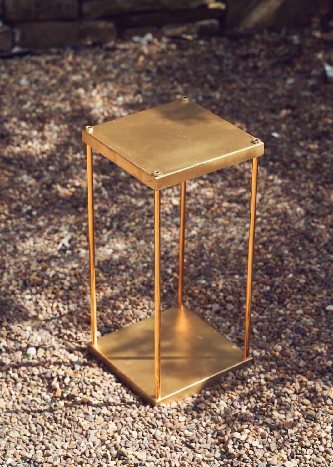 Gold metal plinth with a square top and open frame