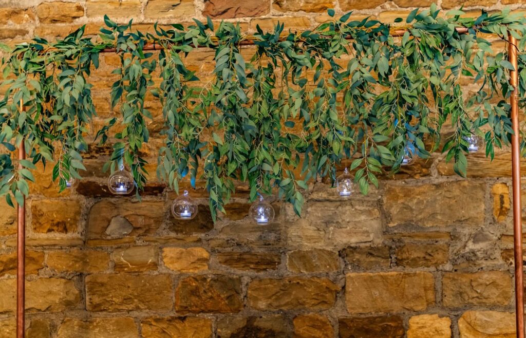 Copper wedding arch hire with cascading greenery and hanging glass baubles