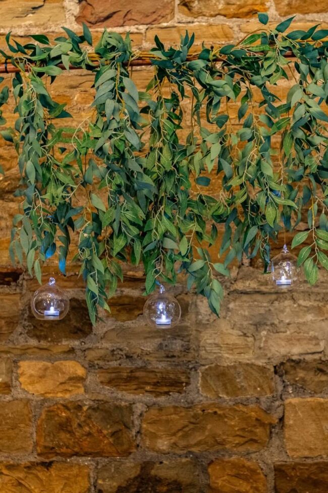 Copper wedding arch hire with cascading greenery and hanging glass baubles