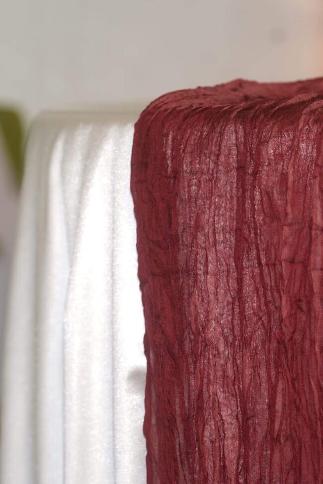 Burgundy cheesecloth runner draped over the edge of a dressed table