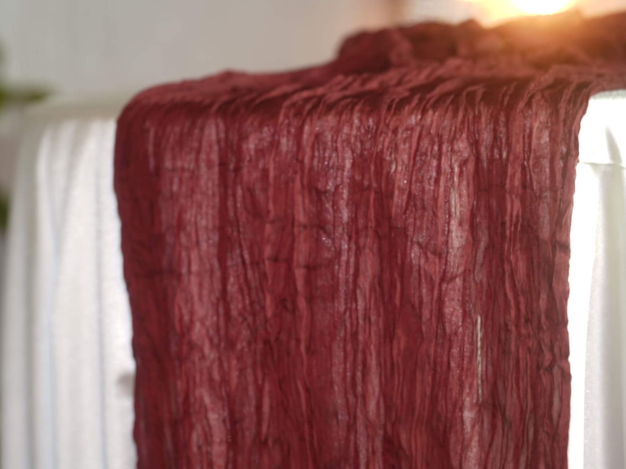 Burgundy cheesecloth table runner styled over a white dressed table