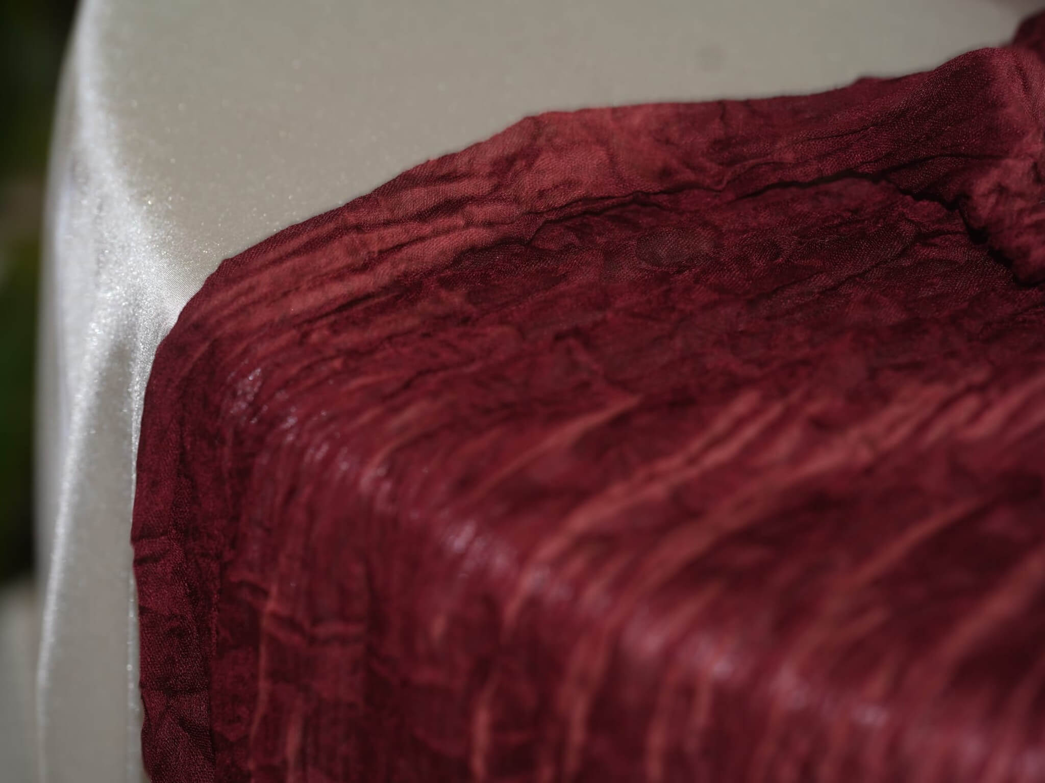 Close-up of burgundy cheesecloth runner fabric texture on a table edge