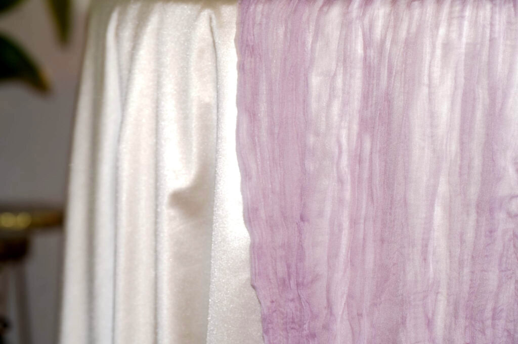 Purple cheesecloth runner draped over the edge of a dressed table