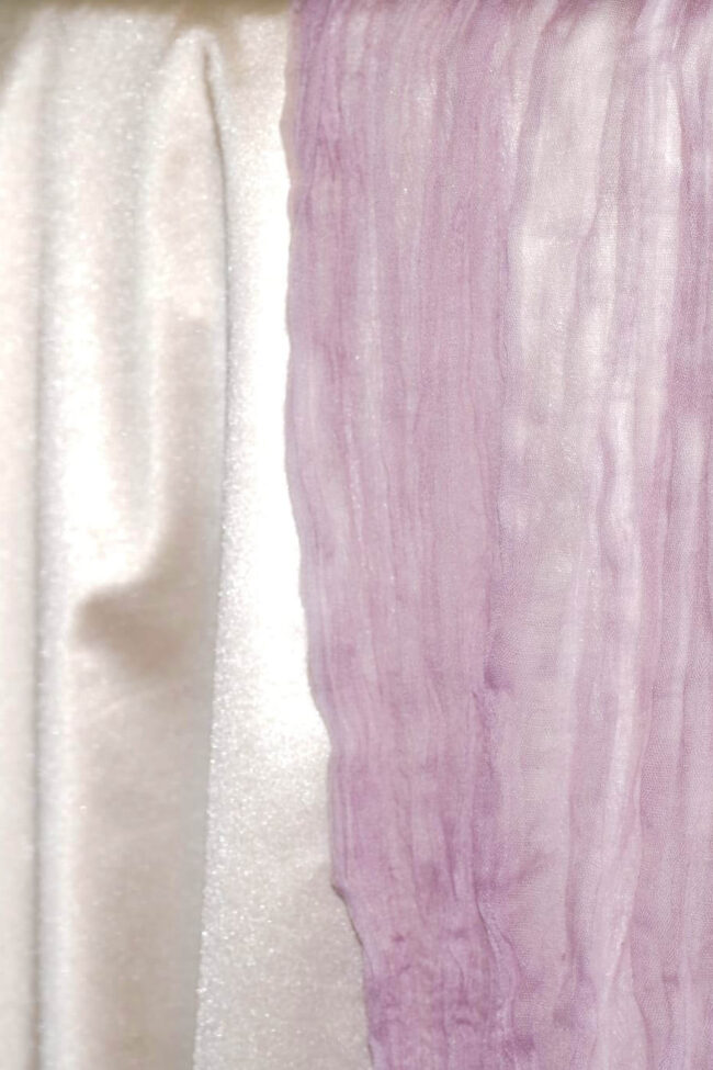 Purple cheesecloth runner draped over the edge of a dressed table