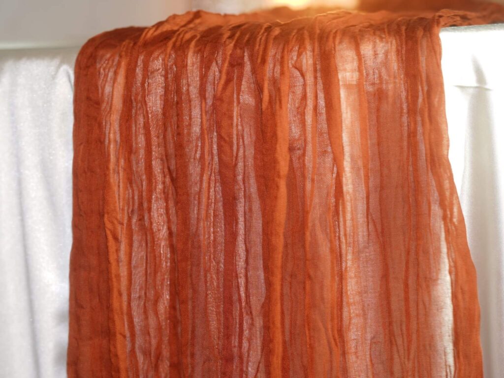 Terracotta table runner in cheesecloth fabric with soft drape detail