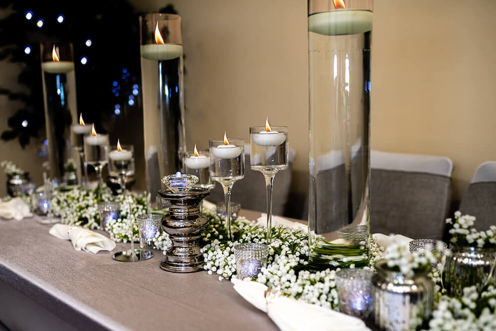 Soft table linens styled with floating candles, silver accents and baby’s breath for a refined wedding table setting.