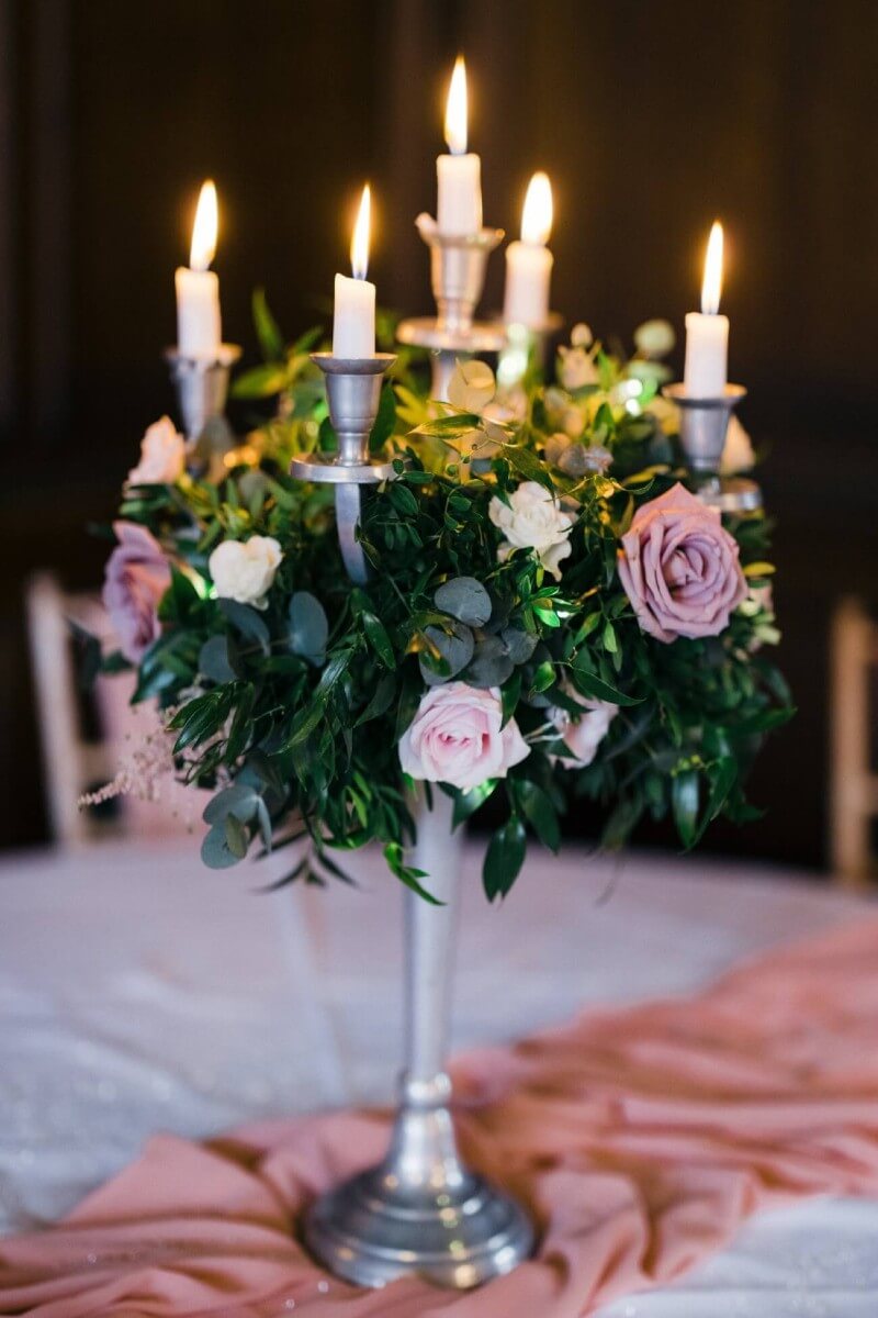 Candelabras for hire with floral arrangement and lit candles.