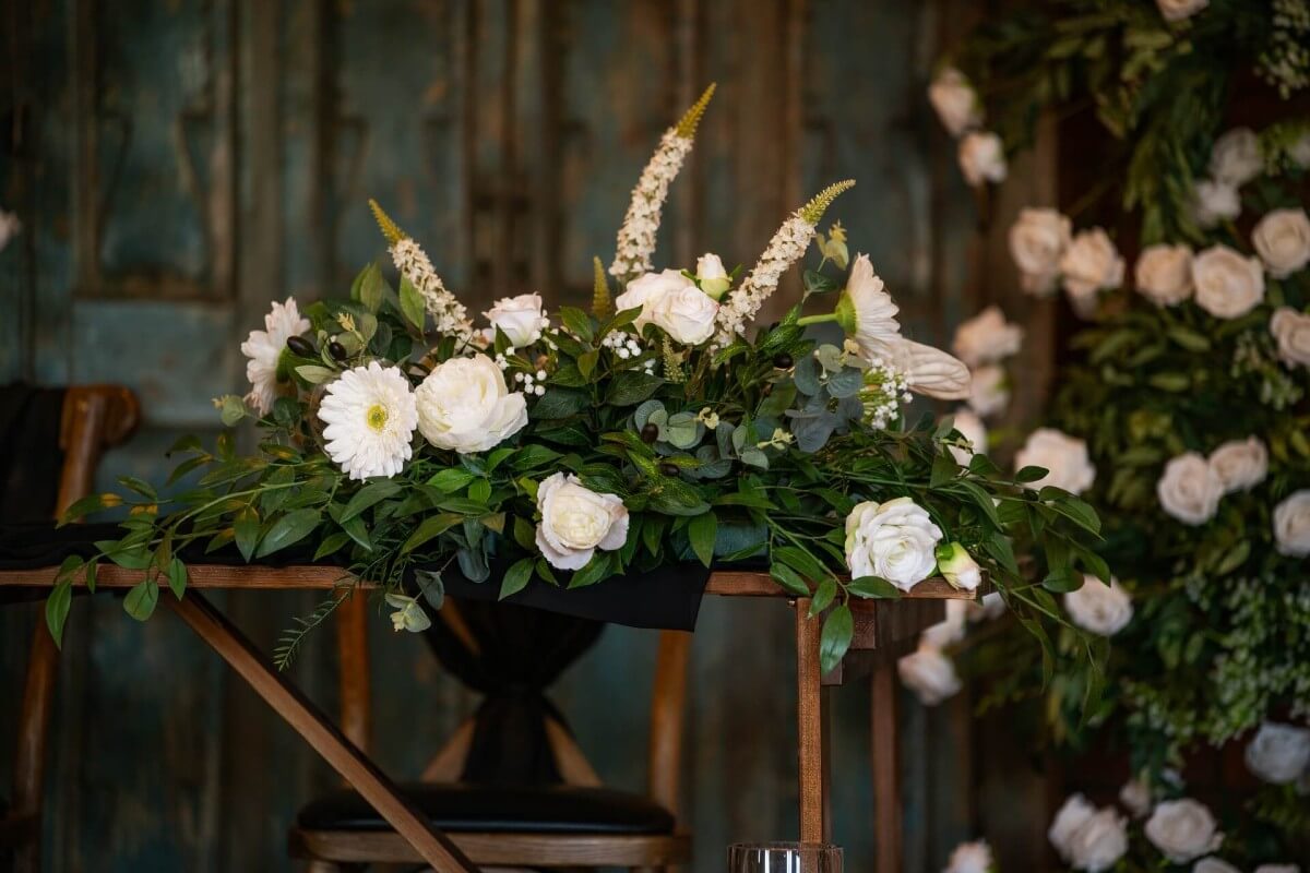 Flower centrepieces with white roses and greenery on a wedding table