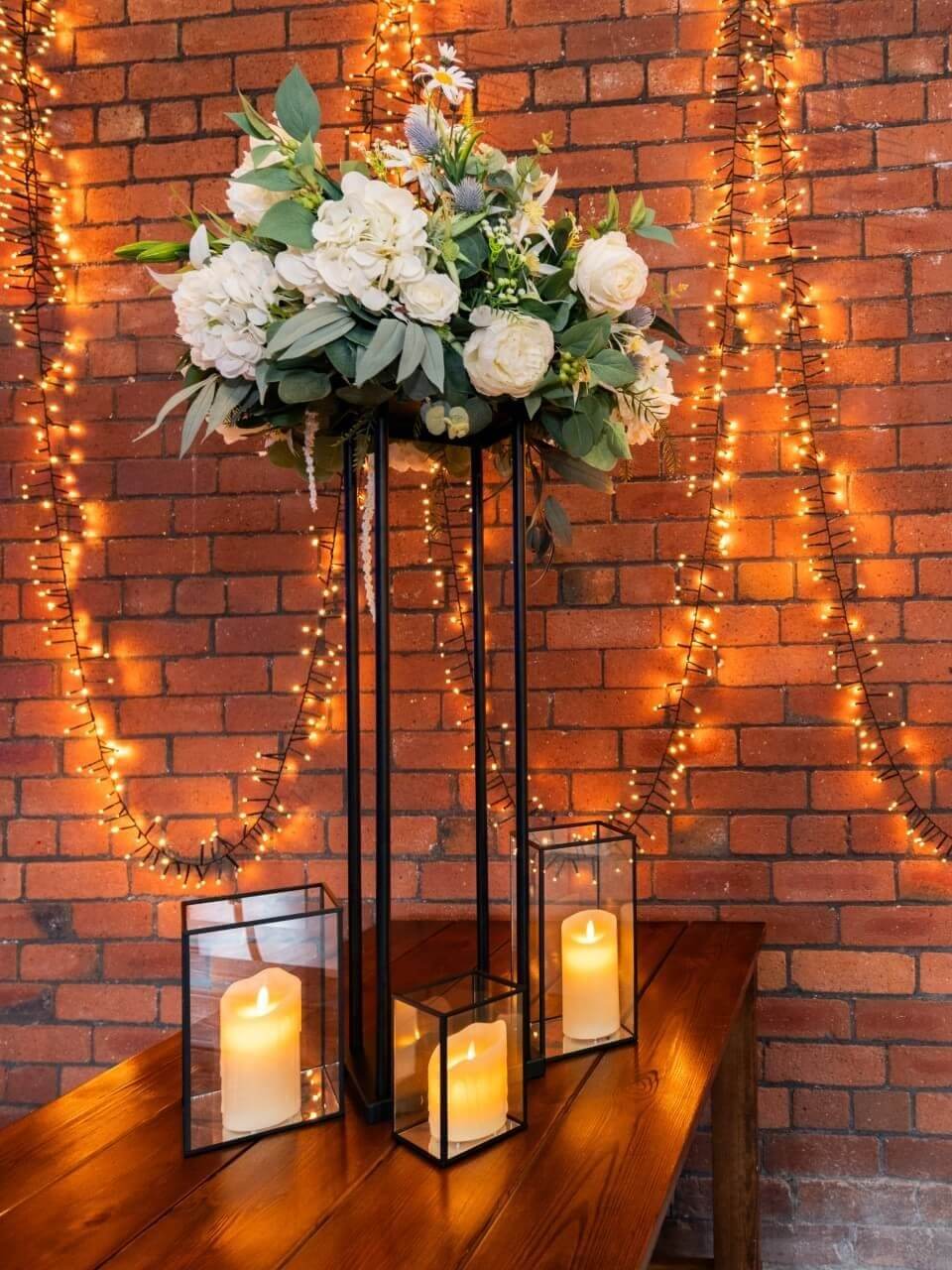 Tall black plinths styled with candles and floral arrangements at an event.