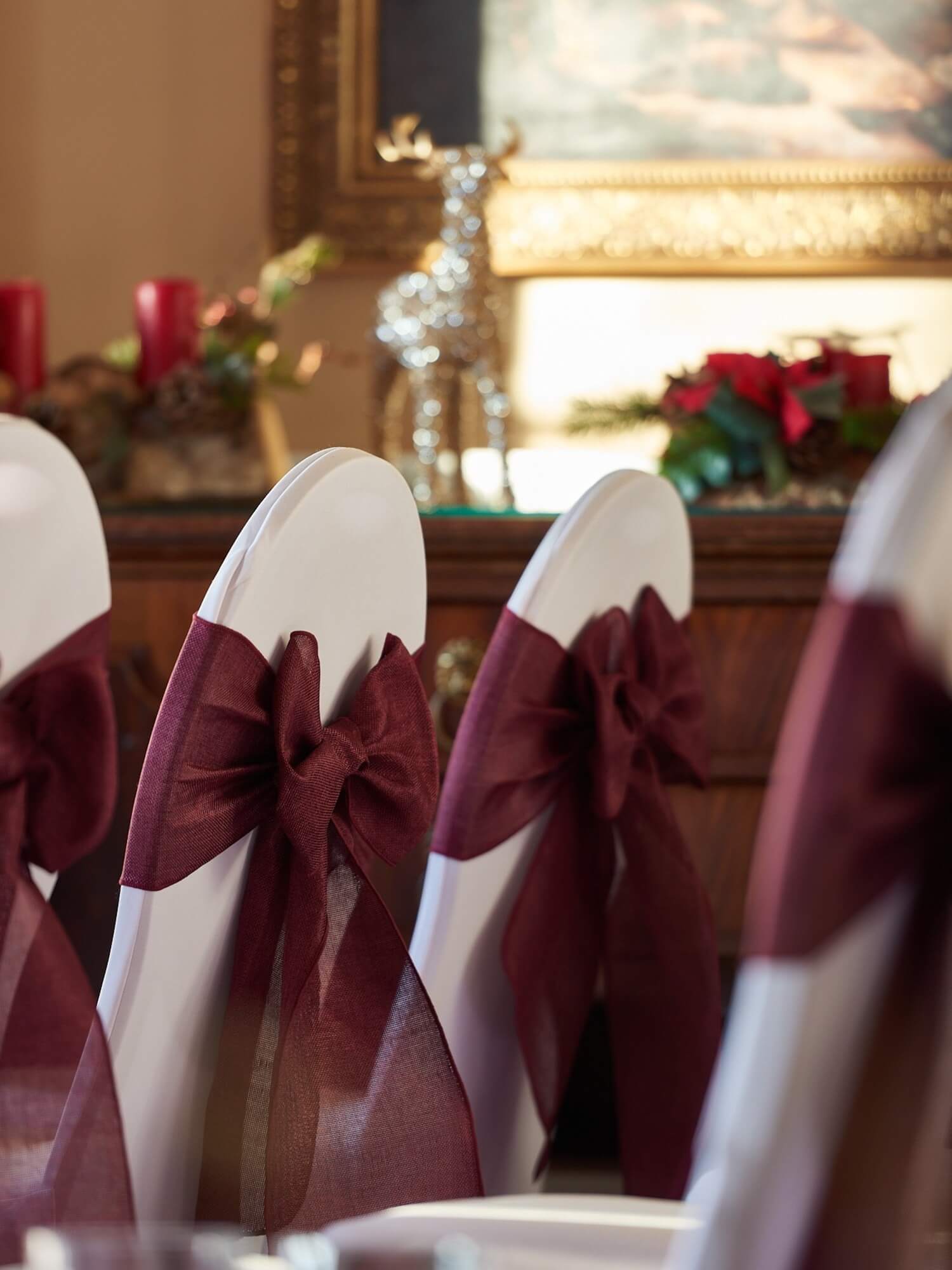 White chairs styled with burgundy bows for an elegant celebration, featured within our wedding packages.