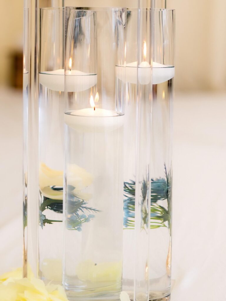 Floating candles in tall glass cylinders used for elegant event styling with props.