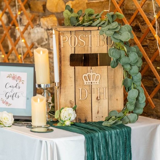 Rustic wooden post box decorated with greenery and flowers as part of an elegant event decor display.