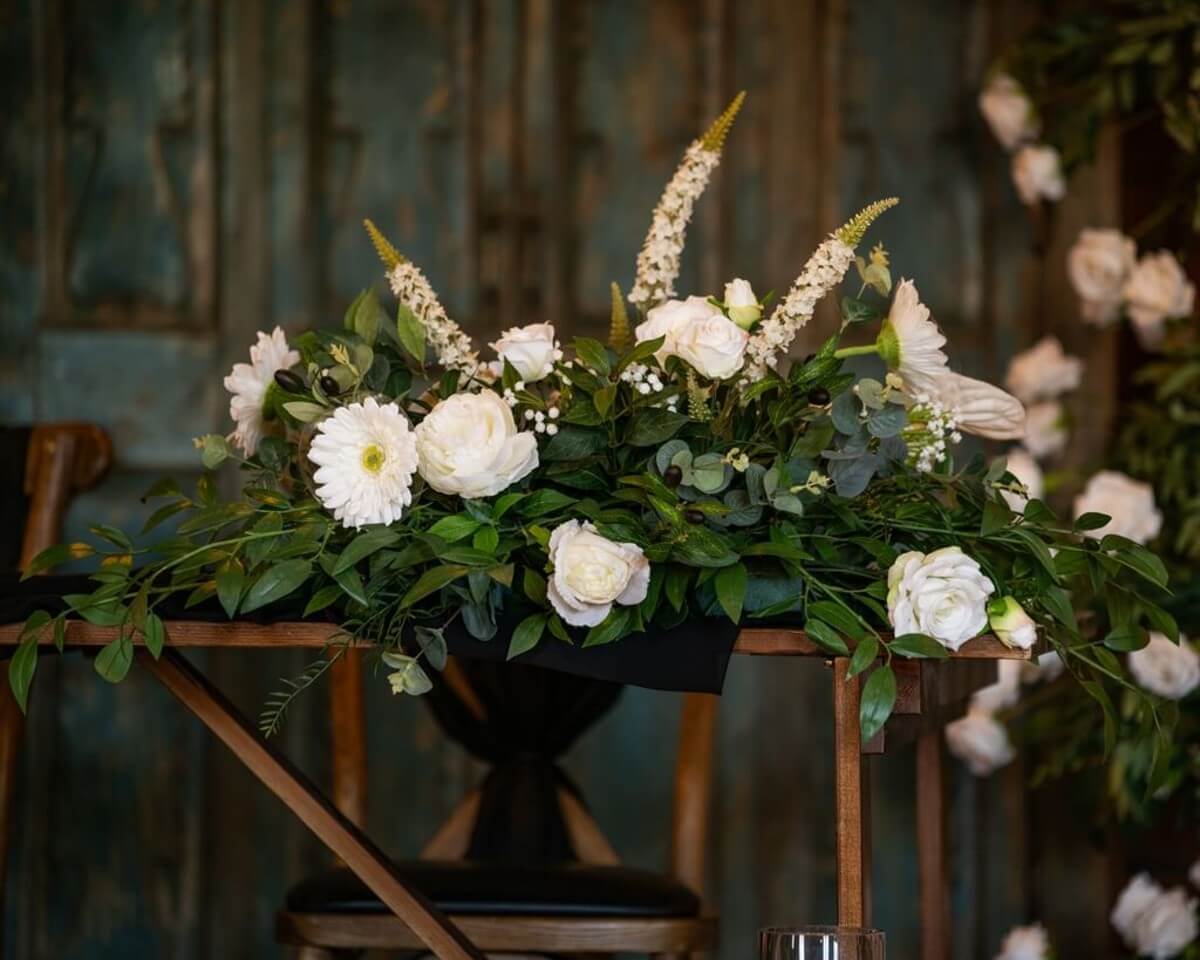 Top table arrangement with white flowers and greenery, styled for elegant event decor hire.