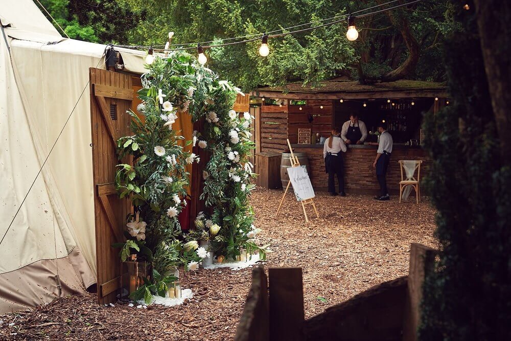 Wedding arch with flowers at rustic outdoor venue entrance.