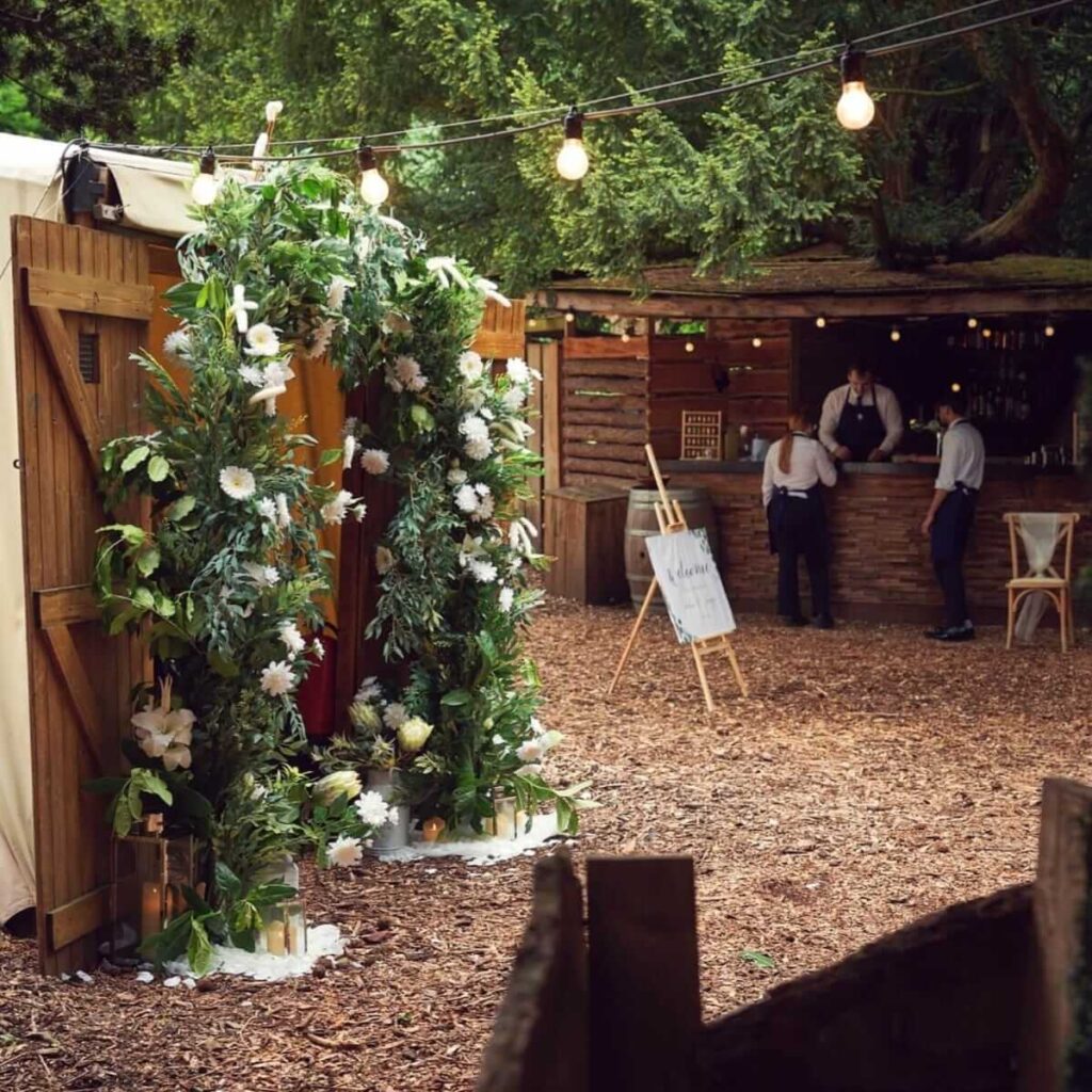 Floral entrance arch and rustic outdoor bar setup, perfect for spring themed celebrations.