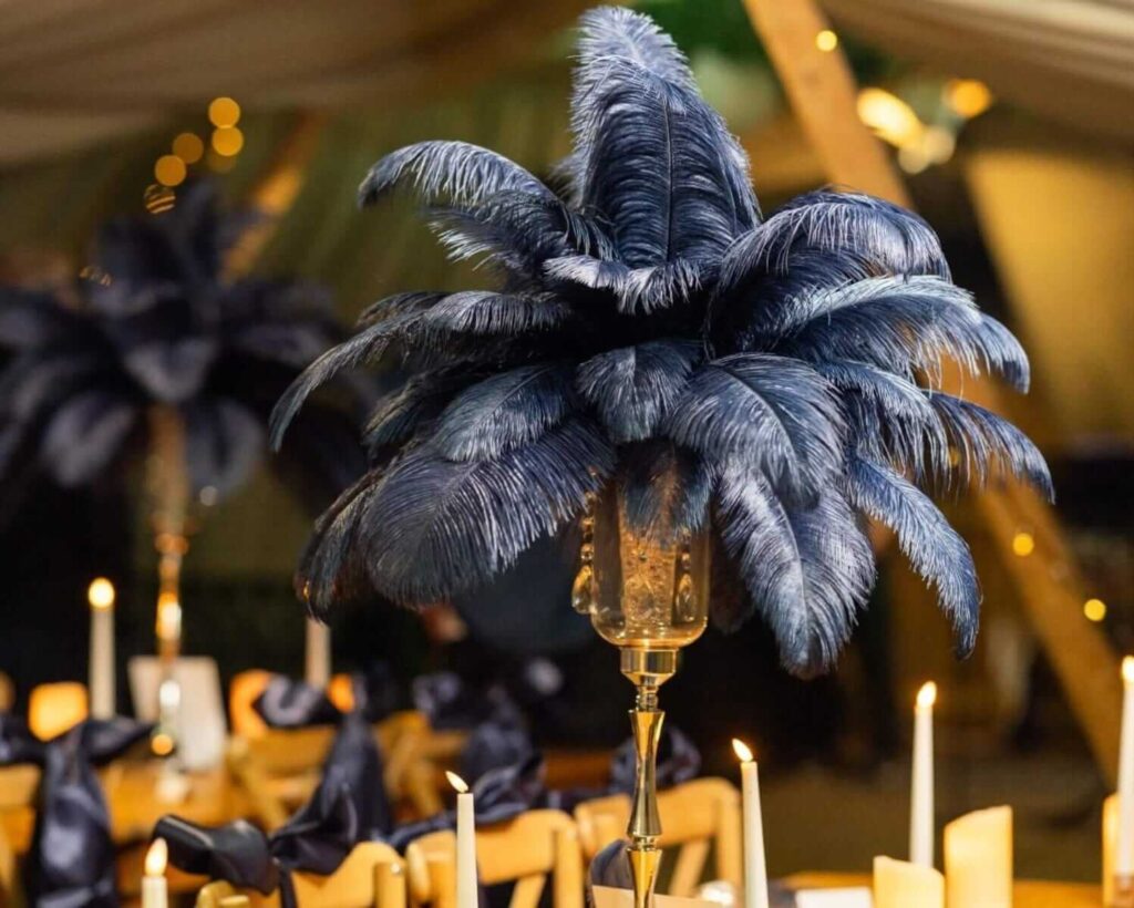 Great Gatsby themed feather centrepiece with black ostrich plumes and candlelit table styling.