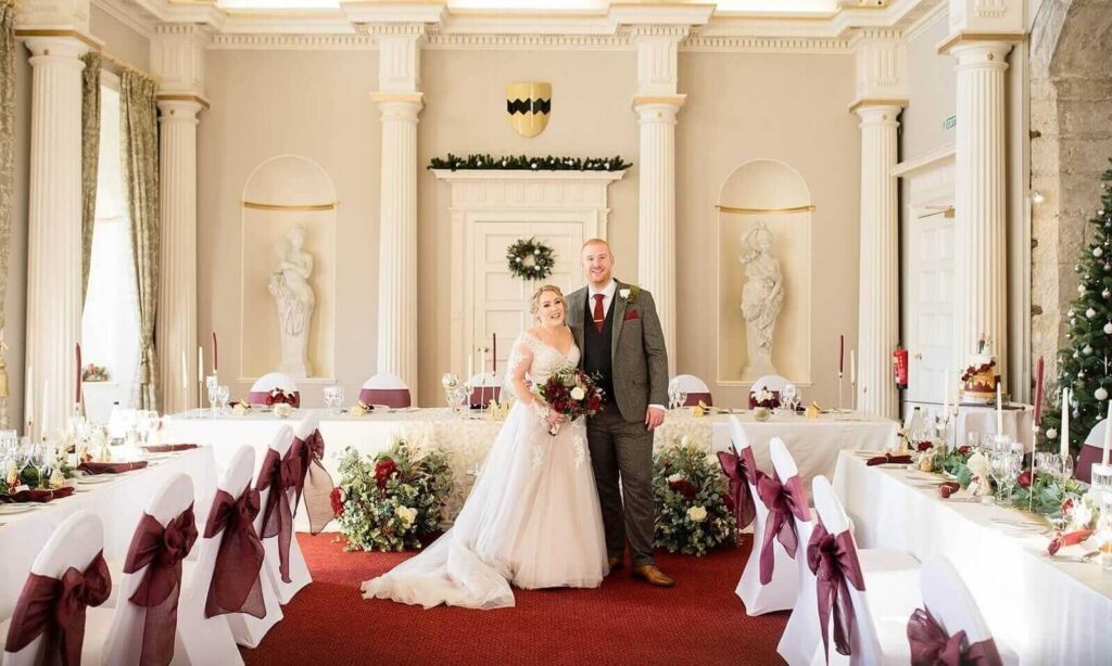 Bride and groom in a beautifully styled venue with burgundy décor and florals showcasing elegant event styling.