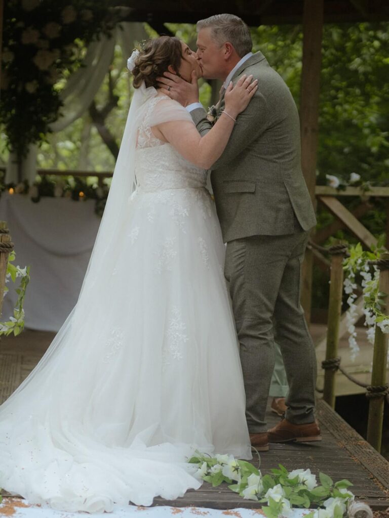 Bride and groom sharing a kiss during their wedding ceremony, creating a beautiful moment with strong visual impact.