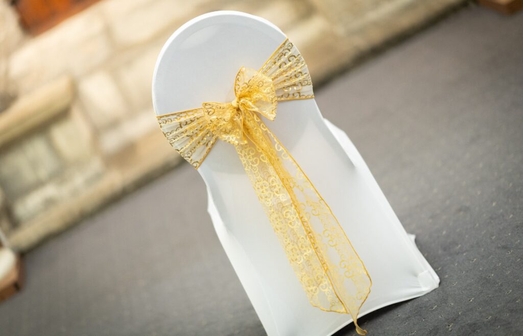 Do it yourself chair styling with white cover and gold organza sash bow.