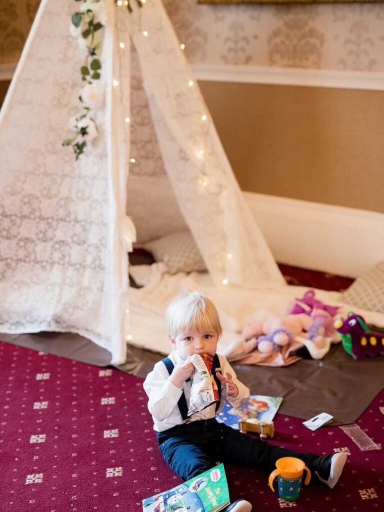 DIY wedding kids teepee play area with a toddler sitting on the carpet.